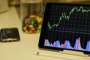 Tablet display of stock market data with smartphone and colorful candies on desk.